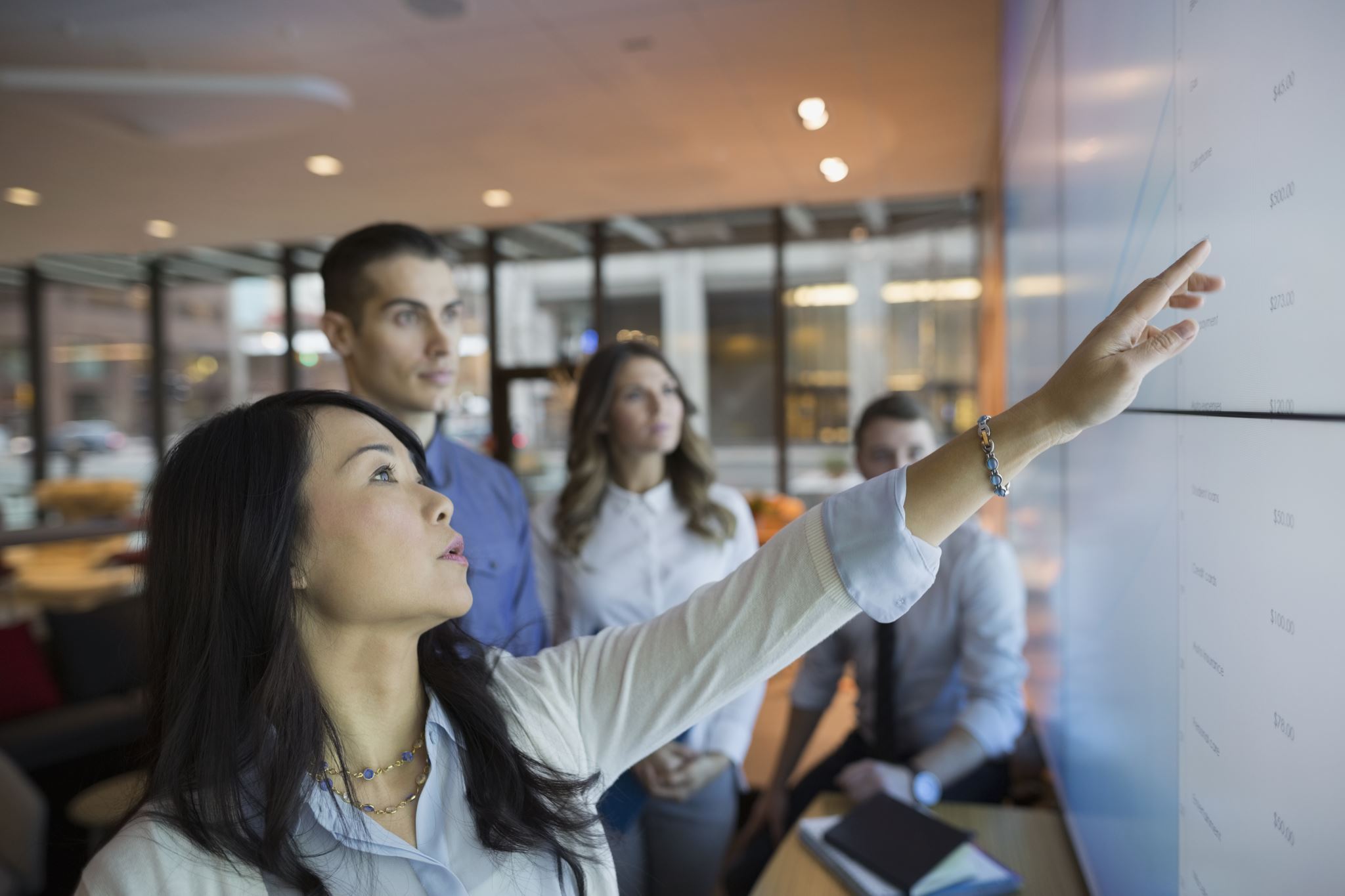 Business-people-in-a-meeting-room-pointing-at-a-projection-screen