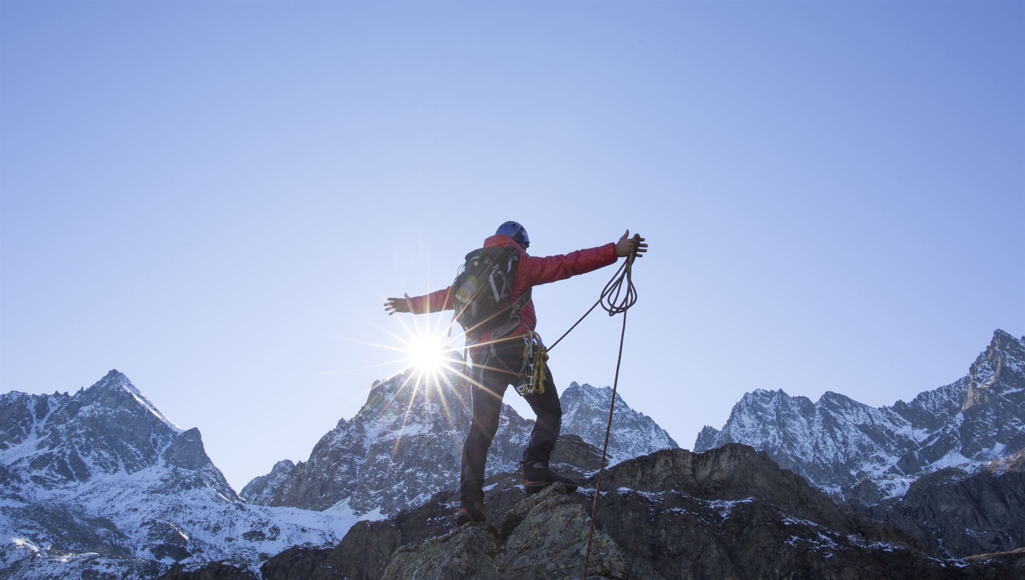 Person-wearing-climbing-gear-standing-on-top-of-mountain