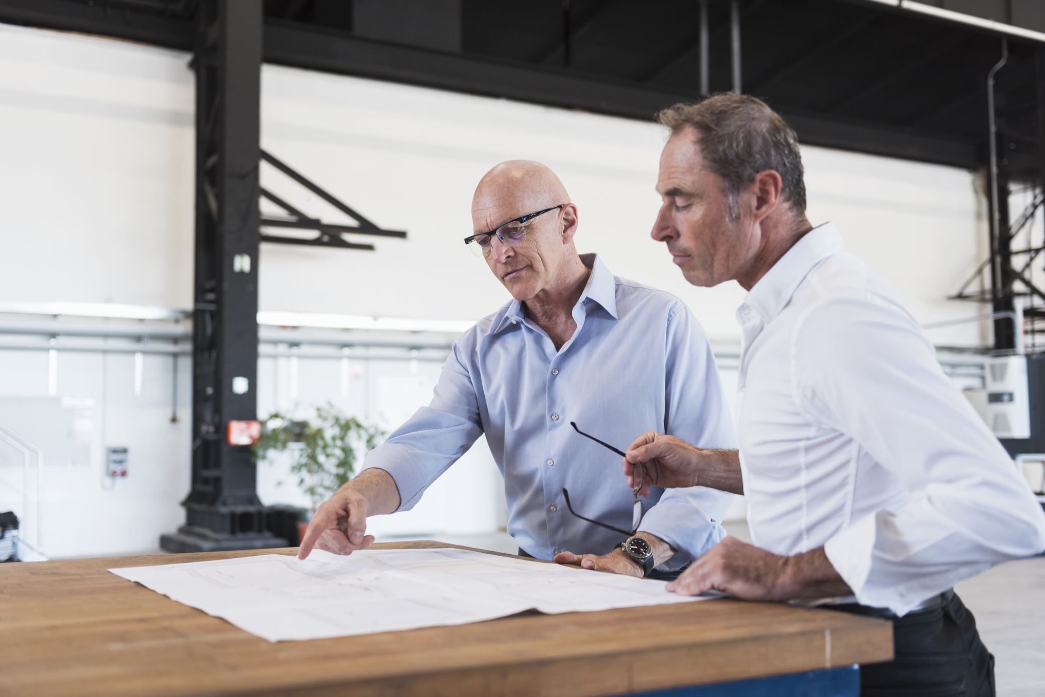 Two-businessmen-looking-at-plan-on-table